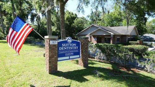 Sutton Dentistry office exterior in Ocala, FL featuring clinic sign, brick building, and American fl