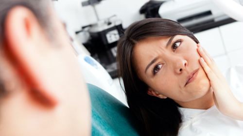 Patient holding jaw in pain from dental emergency before travel in Ocala, FL