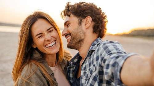 Happy couple smiling outdoors at sunset showcasing healthy, confident smiles from Sutton Dentistry i