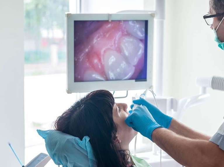 Dentist using an intraoral camera during a dental exam to show real-time tooth images at Sutton Dentistry in Ocala, FL.